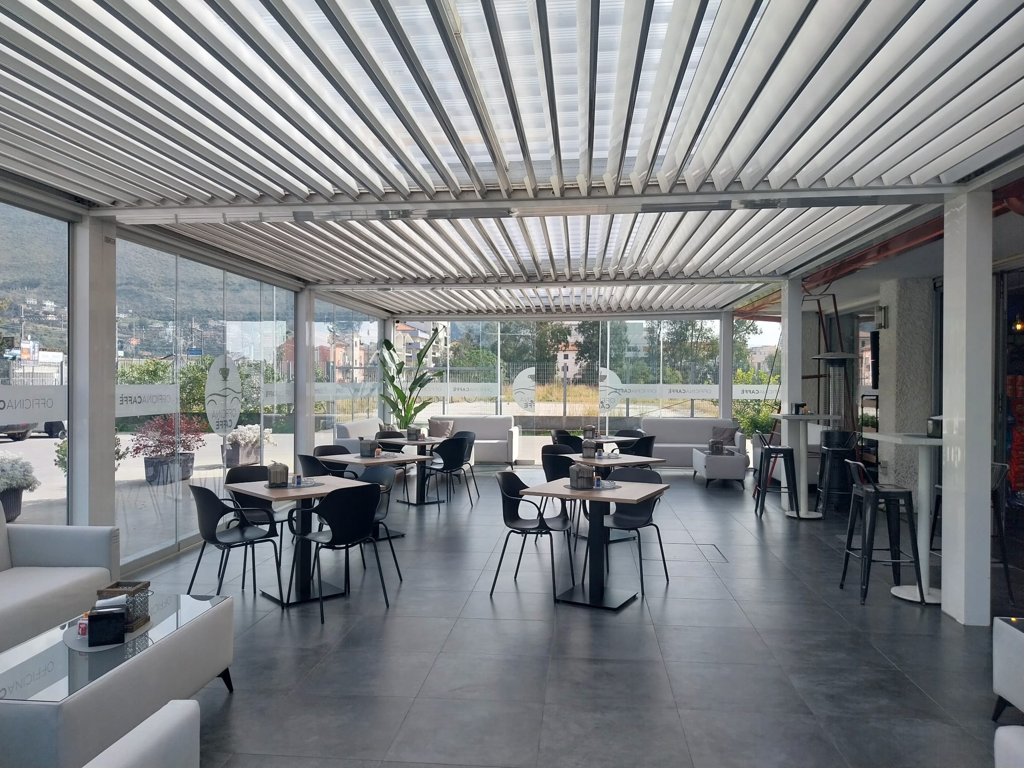 Interno di Officina Caffè con tavoli, sedute e veranda coperta